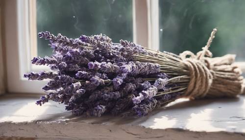 Bunch of dried lavender tied with a rustic twine, placed on a window sill of a stone cottage.