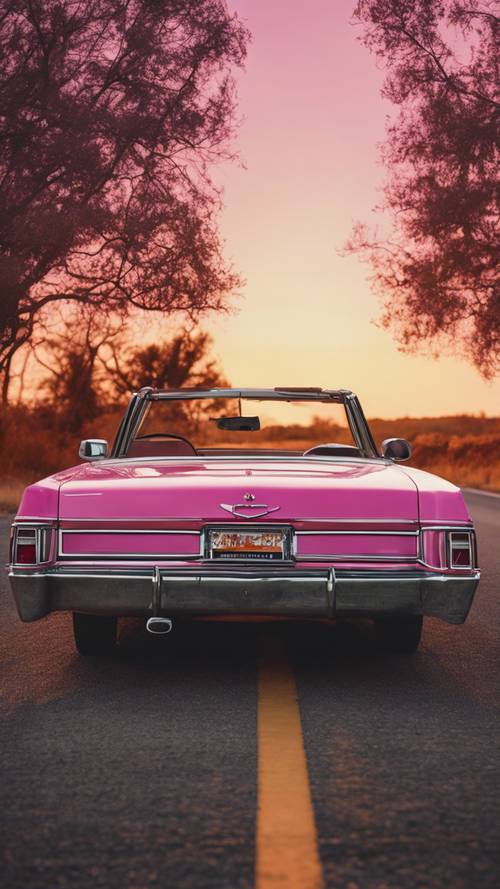 Ein dunkelrosa Oldtimer-Cabrio, das bei Sonnenuntergang auf einem einsamen Highway in den USA geparkt ist.