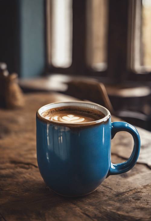 Une tasse à café en céramique bleue sur une table marron rustique.