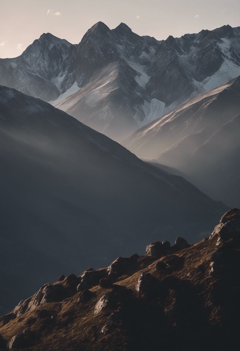 An array of dark gray mountain peaks reaching into a crisp morning sky. Tapet[5342c50b3f954e339a5b]