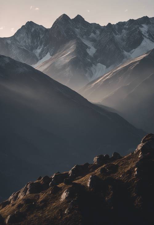 Una serie di cime montuose grigio scuro che si protendono nel frizzante cielo mattutino.
