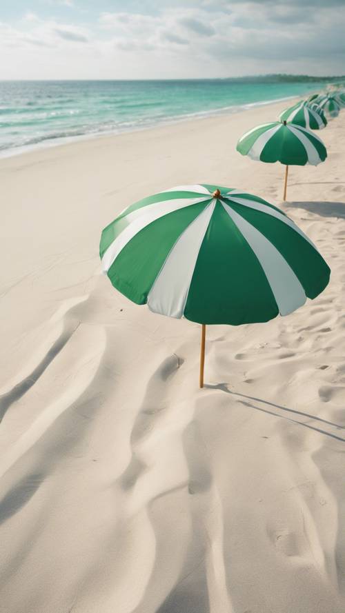 Белый песчаный пляж с зонтиками в зеленую полоску.