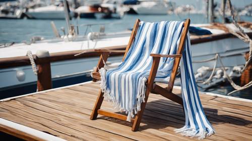 צעיף פסים כחול ולבן עטוף על כיסא נוח מעץ טיק על סירת מפרש.