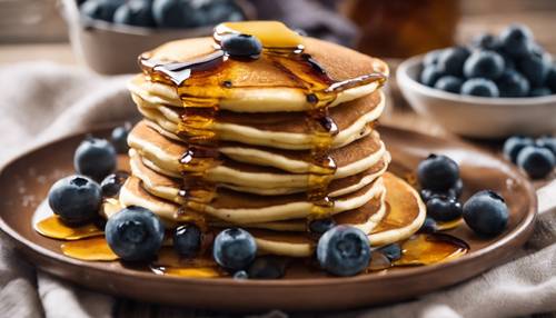 Golden brown pancakes stacked high, topped with glistening maple syrup and fresh blueberries, breakfast in a country kitchen.