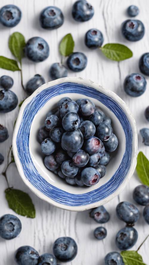 手工制作的蓝白条纹陶器盘，里面装满了新鲜的蓝莓。