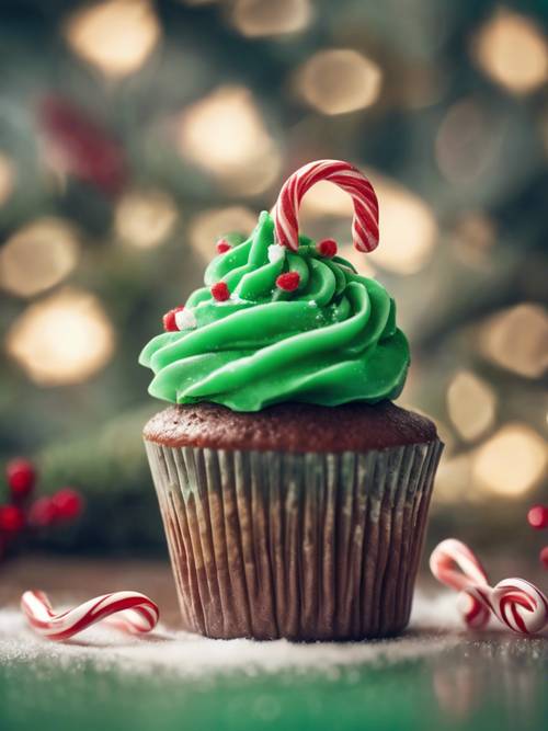 A festive Christmas cupcake with green icing and a small candy cane on top.