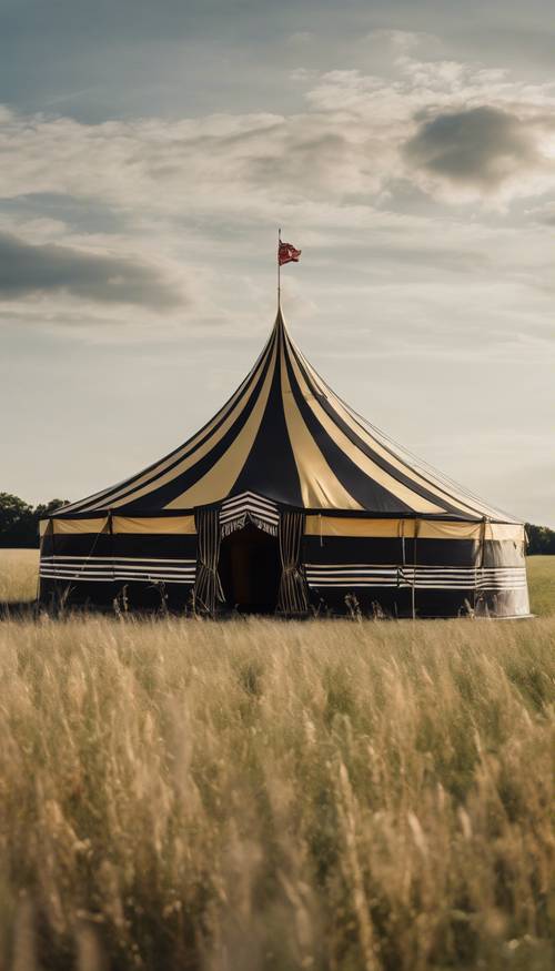 Un chapiteau de cirque flamboyant à rayures noires et dorées se dressant majestueusement dans un champ ouvert et herbeux.