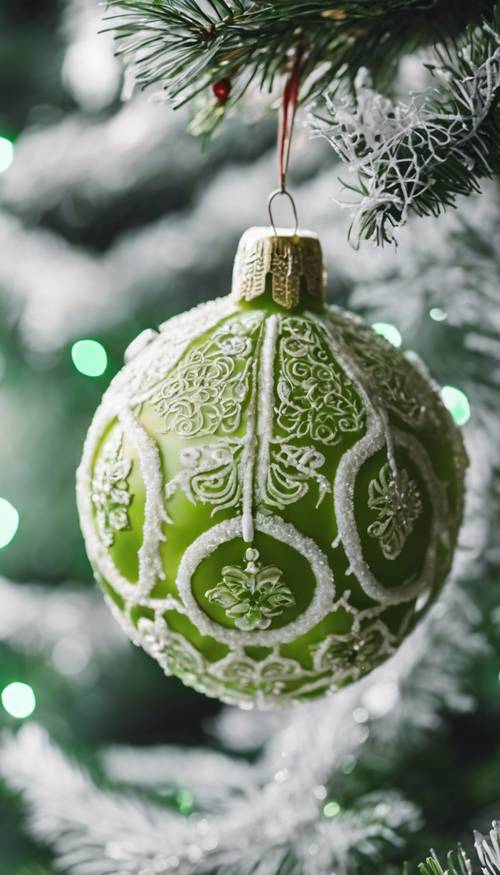 An elegant lime green vintage Christmas ball ornament with intricate white designs, hanging from an evergreen branch.