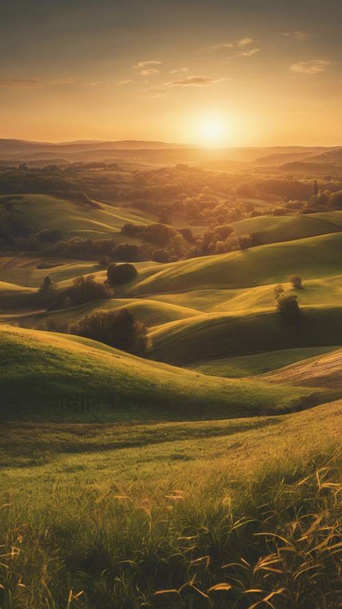 Ein Panoramablick auf einen ländlichen Hügel bei Sonnenaufgang, die goldene Sonne taucht langsam hinter den Hügeln auf.