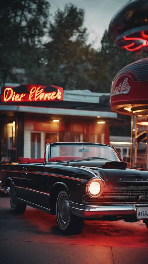 A black convertible classic car with streaks of red flames on the sides, parked in front of a vintage diner.