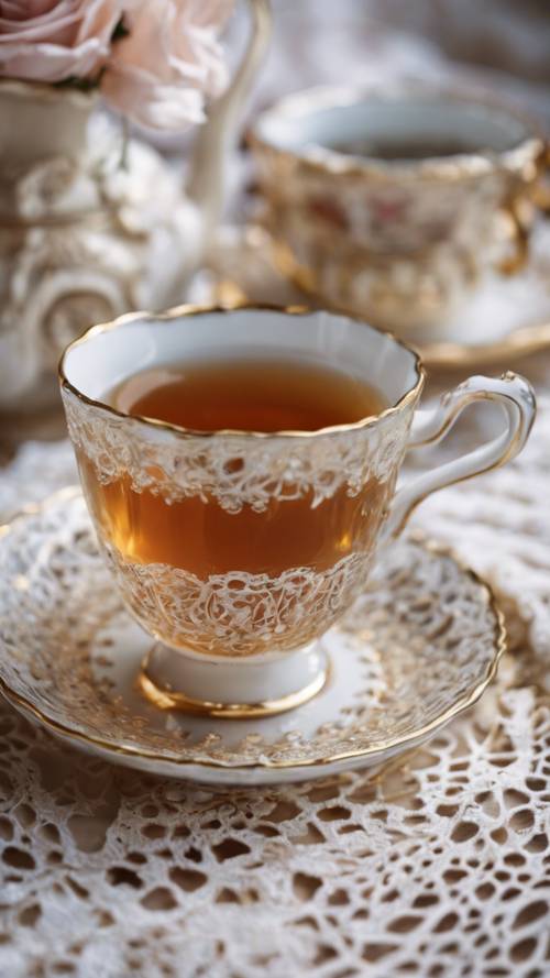 Eine zierliche Teetasse und Untertasse auf einer Spitzentischdecke mit „Tee: eine Umarmung in einer Tasse“, die in der aufgebrühten Flüssigkeit schwimmt.