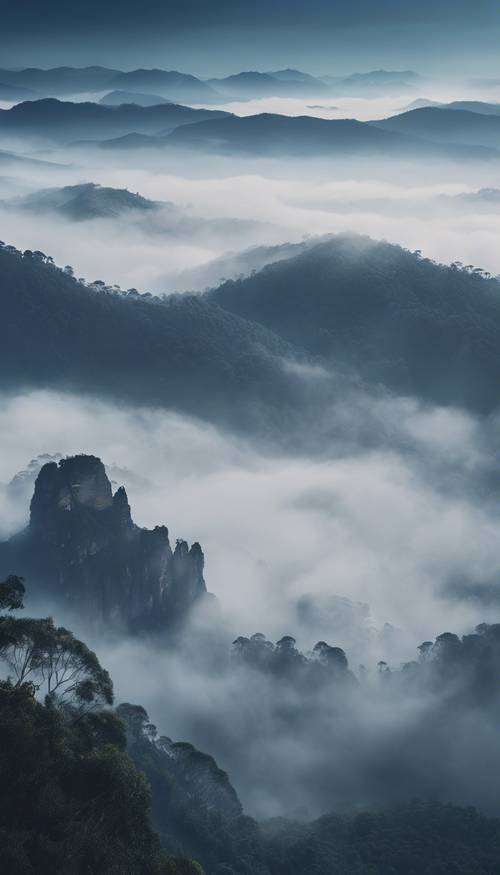 Blue Mountains engulfed in swirling fog, creating a mysterious atmosphere. Tapet [64eb085b4d5c41afbd1f]