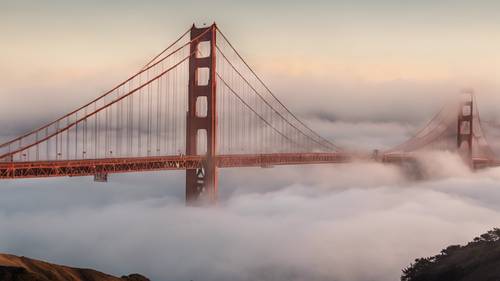 The San Francisco skyline shrouded in a light morning fog, the Golden Gate Bridge peeking through mysteriously.