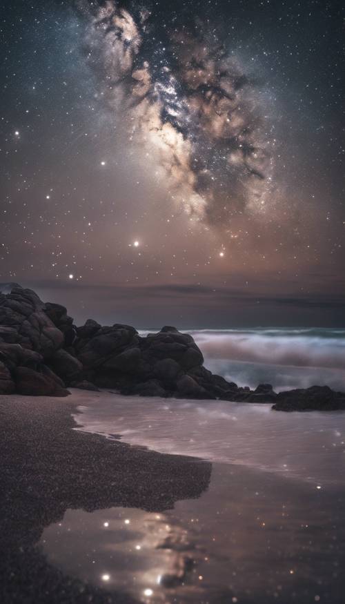 Ein unberührter Strand unter dem Nachthimmel, am Himmel funkeln die Sterne und ihre Spiegelbilder tanzen im Wasser.