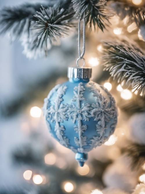 Una decorazione natalizia blu pastello appesa a un albero di Natale innevato.