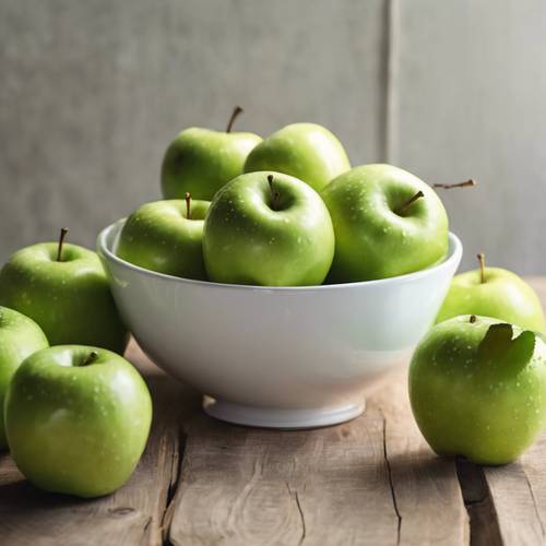 Green apples in a white ceramic bowl on a wooden table.