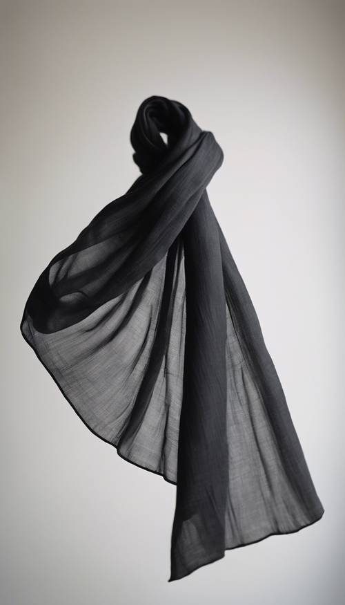 Una morbida sciarpa di lino nero fluttua dolcemente a mezz&#39;aria su uno sfondo bianco.