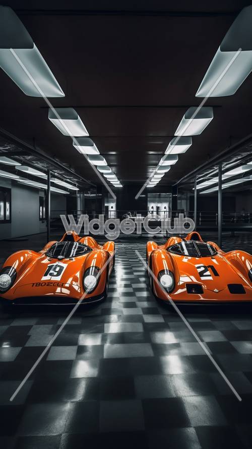 ハイテクガレージにある2台のオレンジ色のレーシングカー