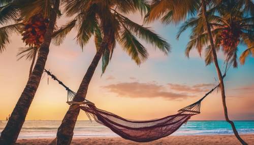 Pemandangan pantai yang indah dengan tempat tidur gantung digantung di antara dua pohon palem di bawah langit berwarna permen saat matahari terbenam.