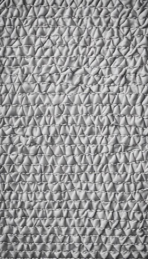 Pola abu-abu geometris pada kain katun putih.