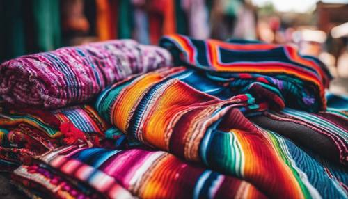 Una pila de coloridas mantas de sarape mexicanas tejidas a mano en un bullicioso mercado al aire libre