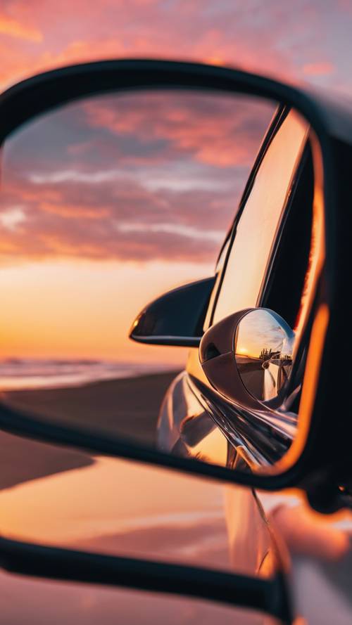 A side view mirror of a sports car reflecting a beautiful coastal sunset.