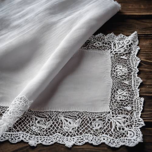 Saputangan linen putih antik dengan pinggiran renda yang rumit, dipajang di permukaan kayu gelap.