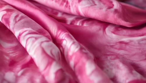Uno scatto dettagliato di un motivo tie-dye rosa su una sciarpa di seta.