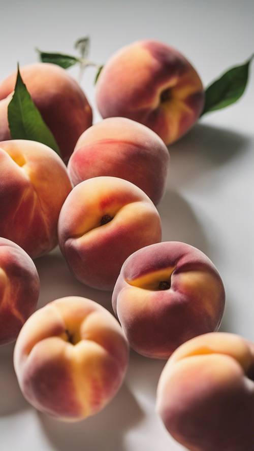 Japanese peaches freshly picked on a minimalist white background.