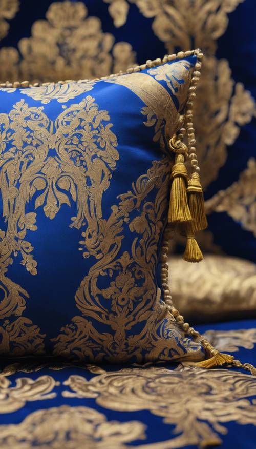 Ein Kissen mit königsblauem und goldenem Damastmuster und Quasten an jeder Ecke.