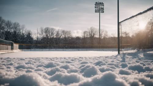A baseball field covered in a thin layer of snow during off-season.