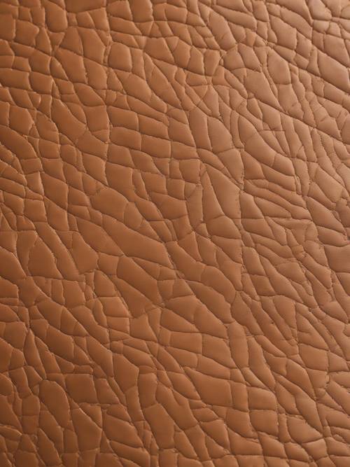 A close up detail of textured tan leather with visible creases and imperfections.