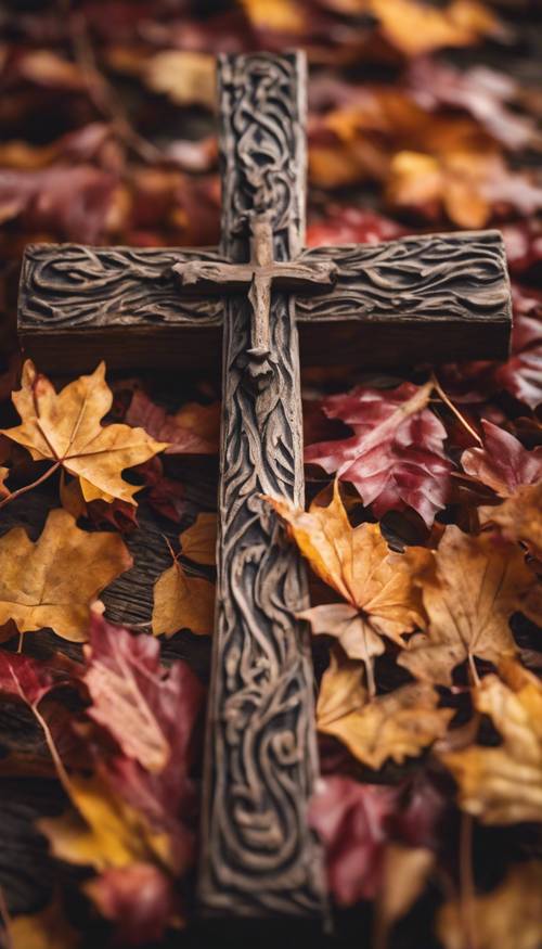Salib kayu berukir tangan pedesaan dengan dedaunan musim gugur yang cerah berjatuhan di sekitarnya.