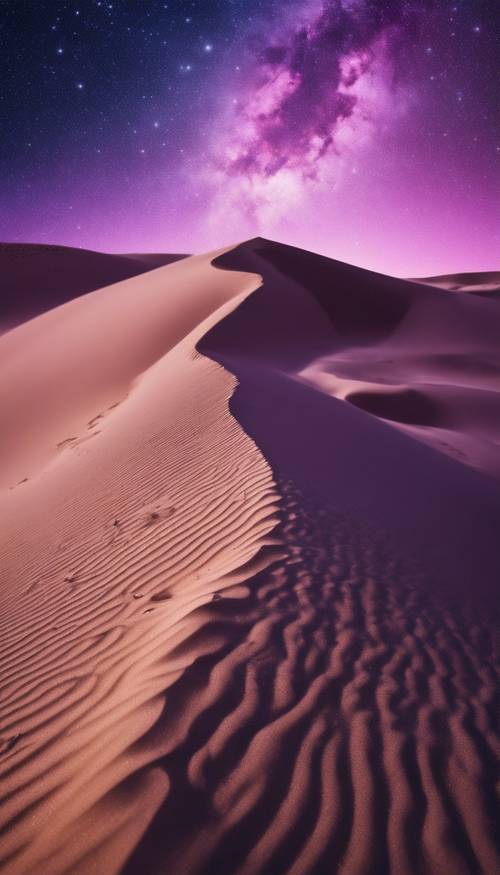 A sand dune under the beauty of a purple night sky filled with stars.