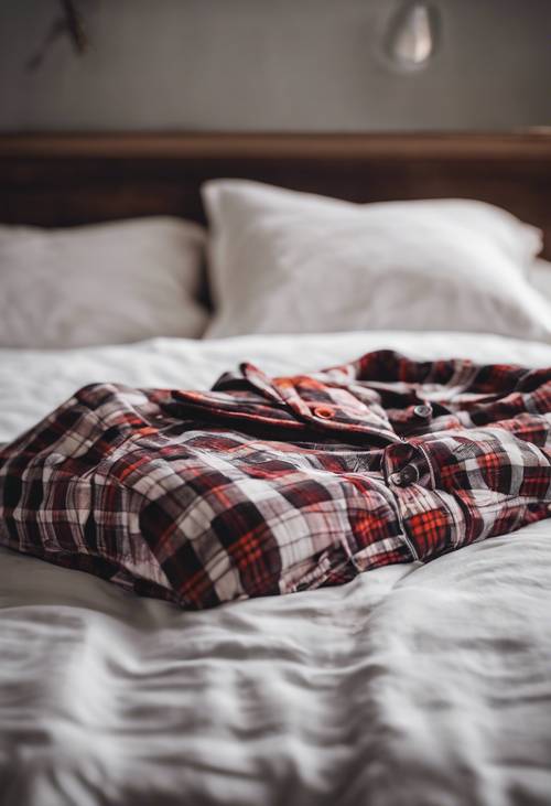 Un ensemble de pyjama à carreaux en flanelle sur un lit fraîchement fait avec des draps blancs.