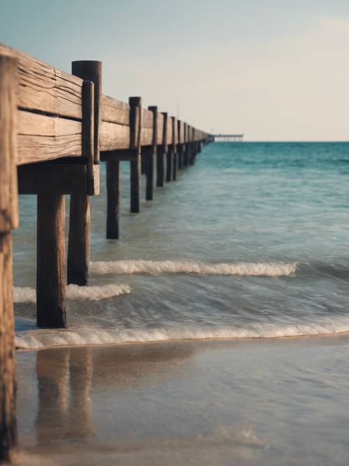 A panoramic view of a beach with a long wooden pier jutting out into the calm sea.