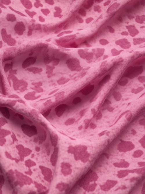 Uma vista de perto de um tecido texturizado com estampa de vaca rosa.