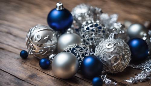 Une pile de décorations de Noël bleu marine et argentées sur une table en bois brillant.