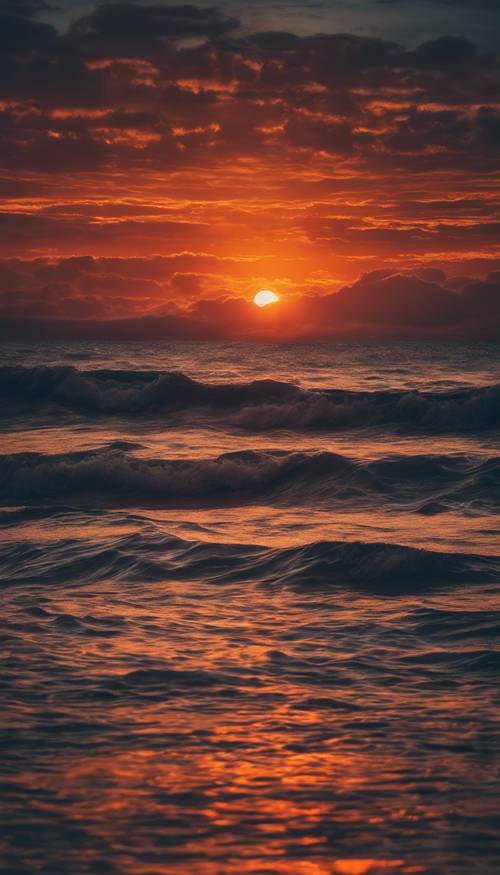Ein leuchtender Sonnenuntergang über dem Meer in den Farbtönen tiefes Marineblau und leuchtendes Orange.