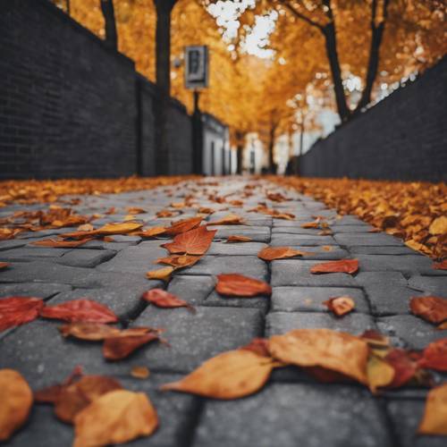 Hojas de otoño cayendo perezosamente sobre un camino hecho de ladrillos de color gris oscuro.