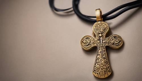 An Egyptian Ankh pendant carved in gold, hanging from a simple leather strap. Tapet [3db7fb1fff6d4613a180]