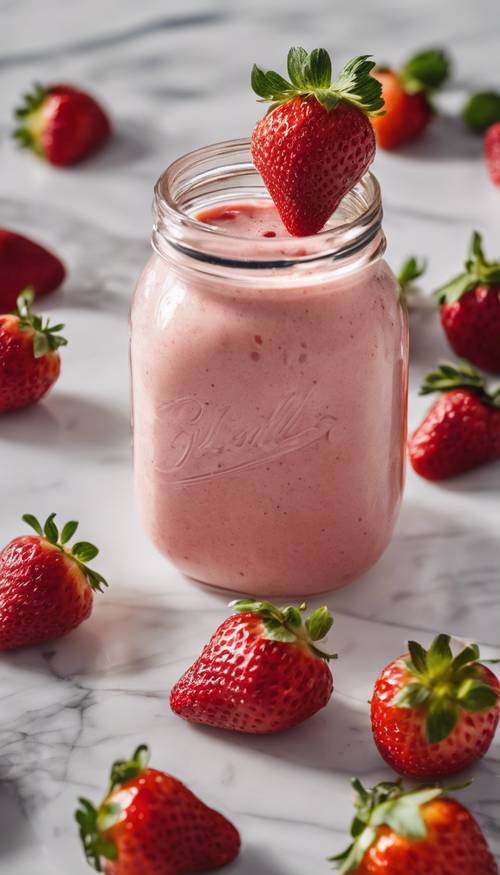 Eine ästhetische Aufnahme eines Erdbeer-Smoothies in einem Einmachglas neben frischen Erdbeeren auf einer Marmorarbeitsplatte.