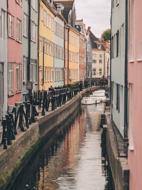 Pastel colored Danish townhouses lining a peaceful canalside.