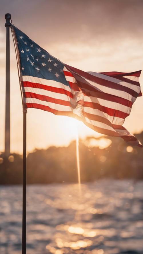 Un tranquilo amanecer del 4 de julio con la bandera estadounidense ondeando suavemente en una suave brisa de verano.