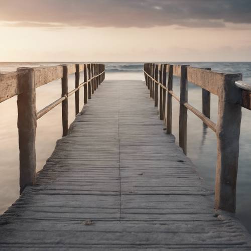 A weathered gray concrete pier stretching out into a calm, tranquil sea at sunrise. Tapeta [8c2cd495d44a46a5adea]
