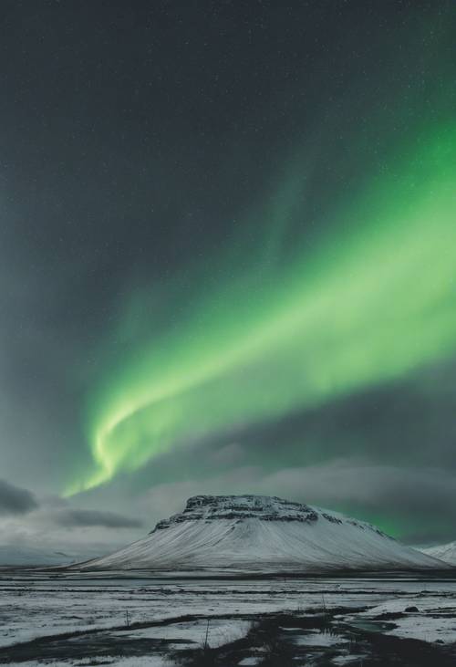 A stunning green aurora borealis illuminating the grey winter sky in Iceland.