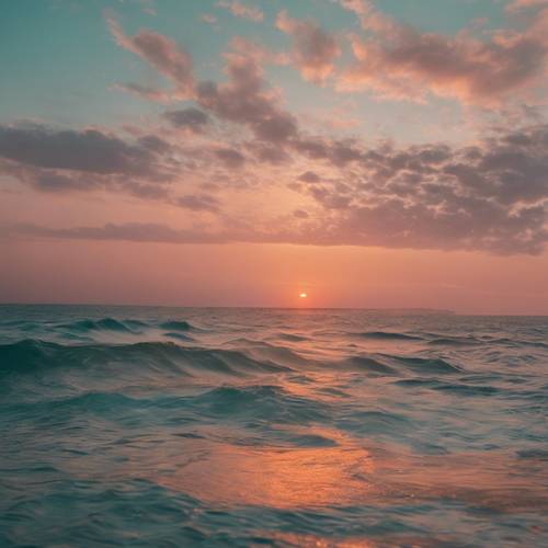 A warm, blush-colored sunset seeping gently into the turquoise waters of the ocean.