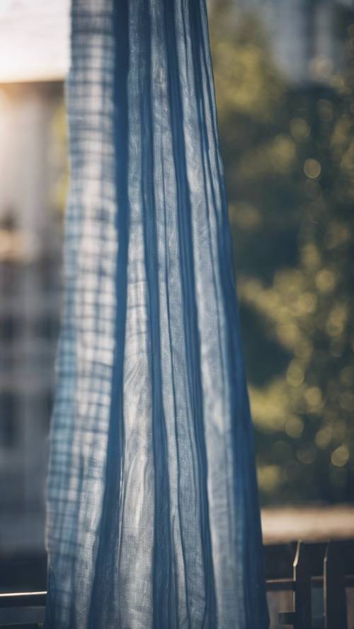 A blue plaid curtain gently blowing in the afternoon breeze.