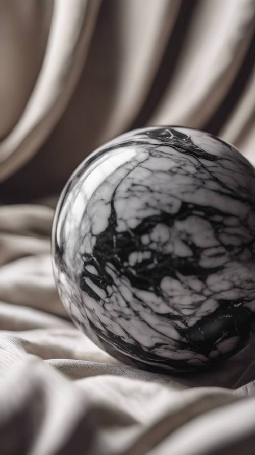 Một quả cầu trang nhã bằng đá cẩm thạch đen và trắng, nằm trên một chiếc đệm lụa.