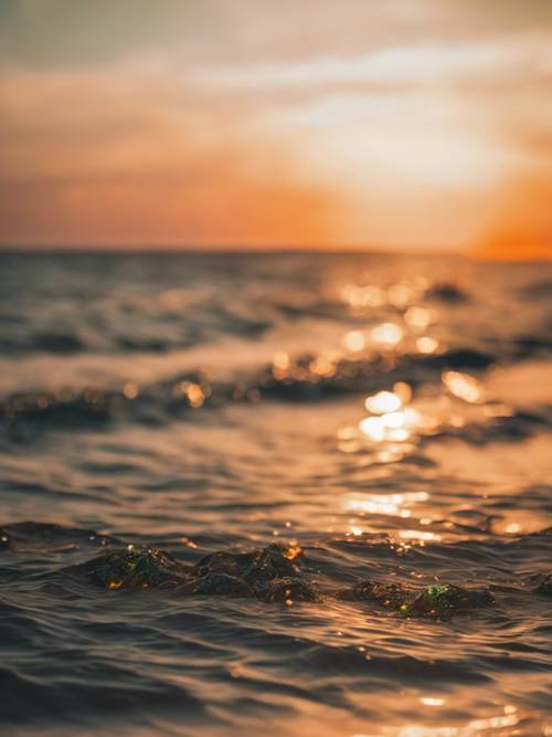 Um pôr do sol cativante, derramando tons de laranja e verde no horizonte sobre um mar tranquilo.